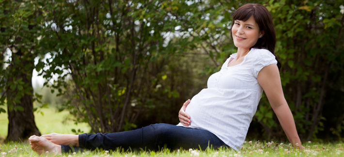 Беременная сидит на траве